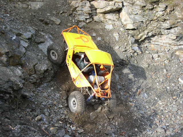 Overhead view of yellow rock buggy with orange cage climbing a rock quarry wall