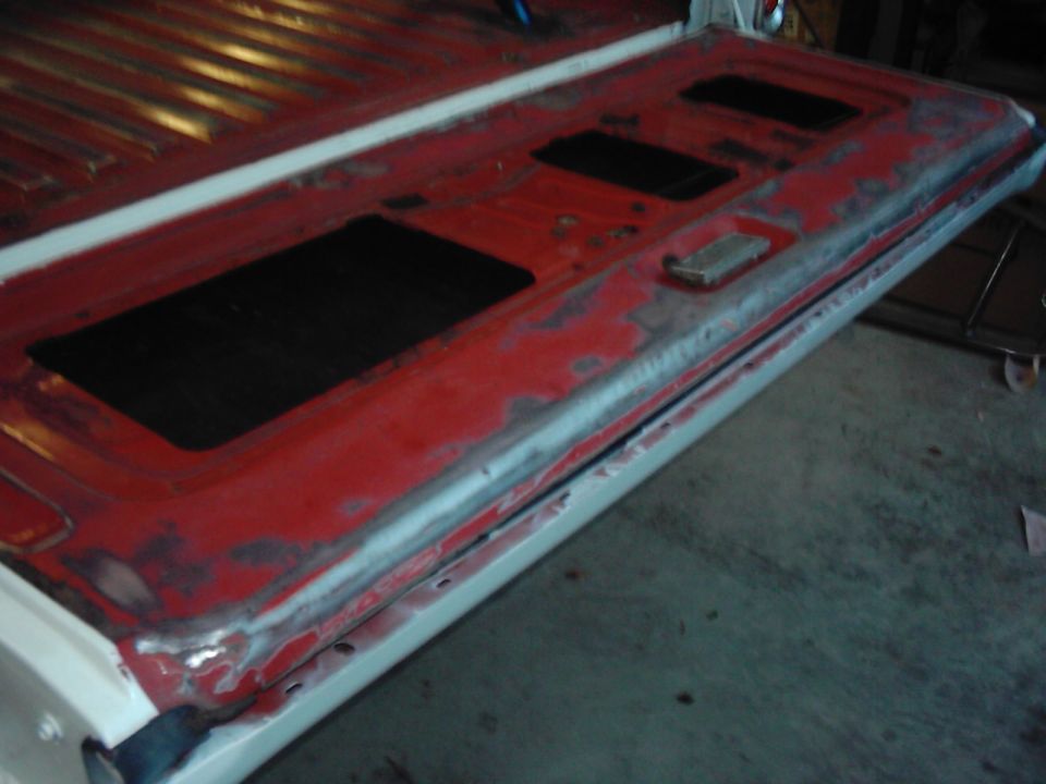 red truck tailgate with black inserts, showing rust and primer