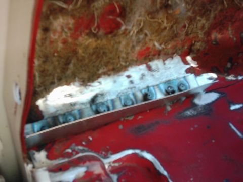 1978 Ford Bronco - Close-up view of a vehicle's interior, showing red painted panels, insulation, and metal bracing.