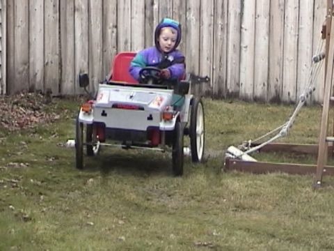 1985 Ford F-150 - A child sits in a toy vehicle, steering it on a grassy lawn.