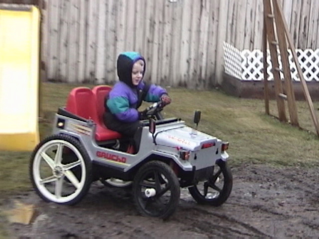 Silver toy jeep with red seats and a child driving