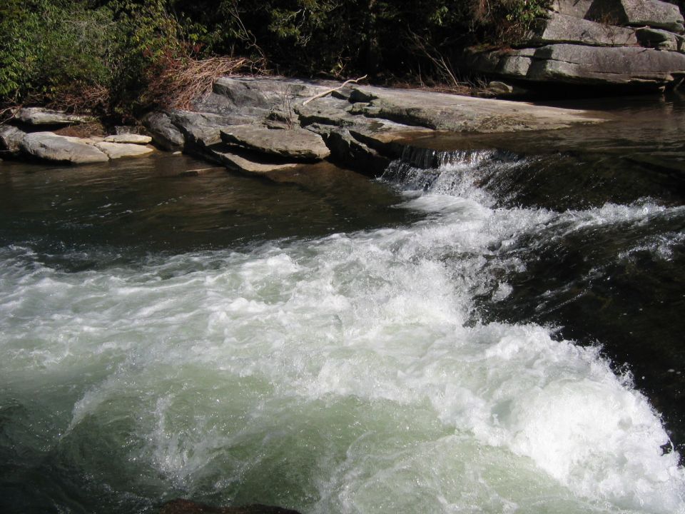 Whitewater rapids cascade over rocks in a natural setting
