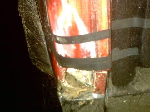 1995 Ford Bronco - Close-up of a damaged and rusted vehicle body panel with black tape.