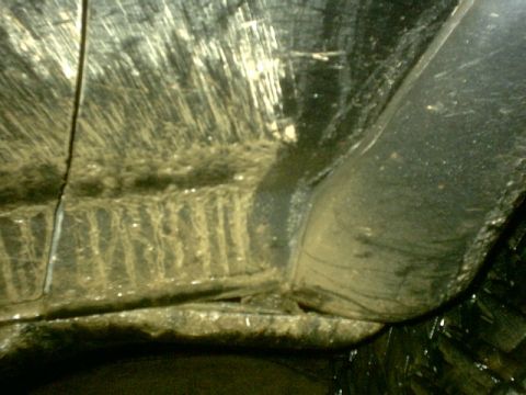 1995 Ford Bronco - The underside of a vehicle is covered in mud and grime, showing the effects of off-road driving.