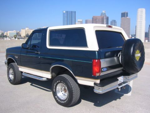 1992 Ford Bronco - This 1992 Ford Bronco is seen from the rear 3/4 angle, a dark green body with a white top and a spare tire mounted on the back.