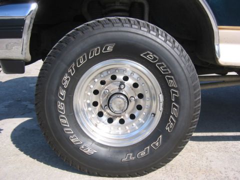 1992 Ford Bronco - A close-up view of a Bridgestone Dueler APT tire mounted on a chrome wheel.