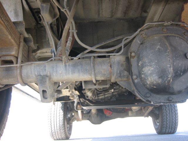 Underside view of a truck's rear axle and differential cover from below on a lift