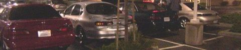 1993 Ford Taurus - A silver 1993 Ford Taurus is parked in a lot at night, viewed from the rear.