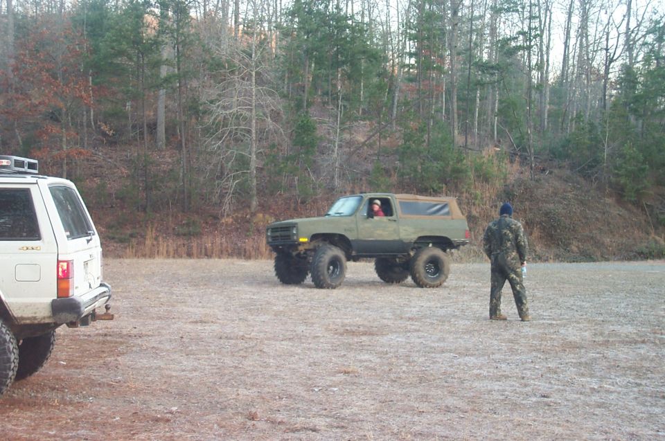 Olive green lifted SUV with large tires, 3/4 front view