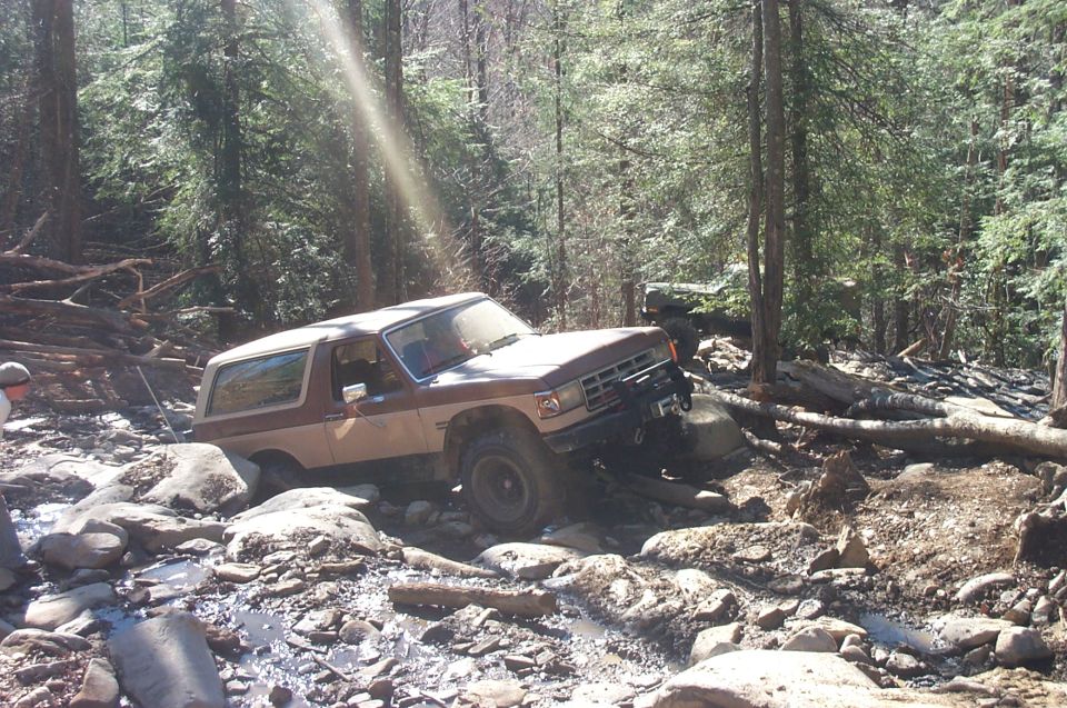 Brown and white 1987 Ford Bronco navigating rocky terrain