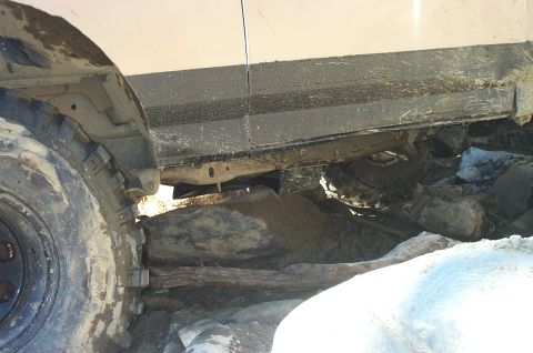 1987 Ford Bronco - This off-road vehicle appears to be stuck on a rocky terrain, with its chassis and tire clearly visible.