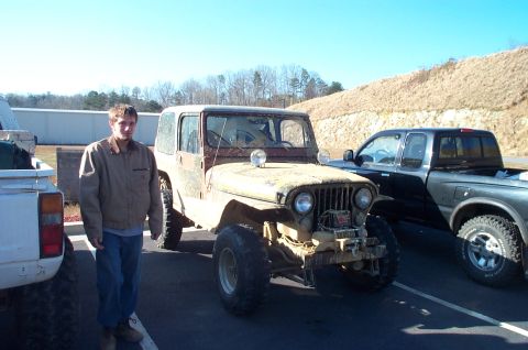 1987 Ford Bronco - A man stands beside a mud-covered Jeep CJ-7, parked next to a white pickup and a black pickup truck.