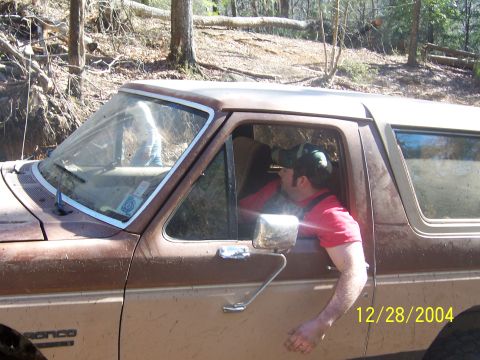 1987 Ford Bronco - Man uses binoculars from inside a 1987 Ford Bronco parked in a wooded area.