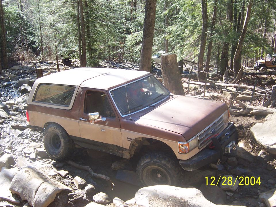 Brown and tan Ford Bronco off-roading on a rocky trail