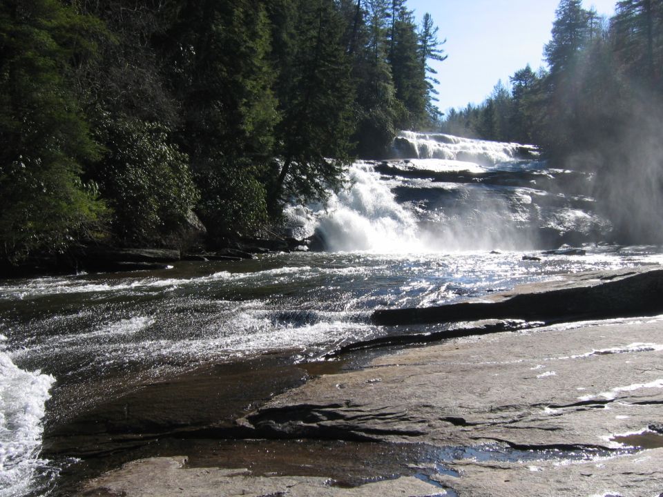 Waterfall cascading over rocks into a river, surrounded by trees