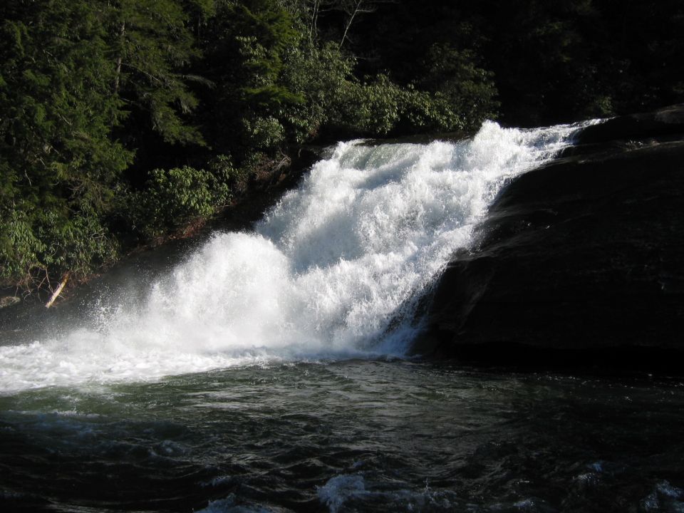 Waterfall cascading over dark rocks with lush green trees in the background