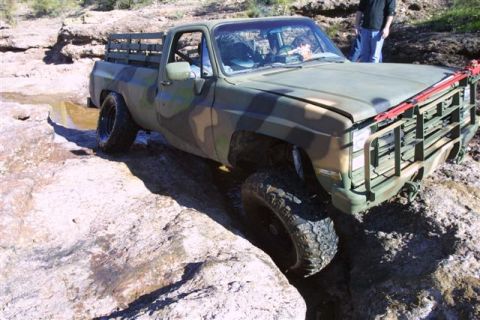 1994 Ford Bronco - This pickup truck, likely from the 1980s, is shown off-roading through a rocky, wet environment.