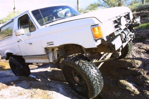 1994 Ford Bronco - This 1994 Ford Bronco is navigating a rocky off-road course with large tires and a winch.