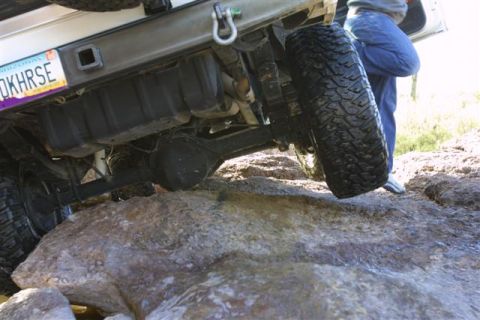 1994 Ford Bronco - Off-road vehicle navigating rocky terrain, focusing on the undercarriage and suspension components.