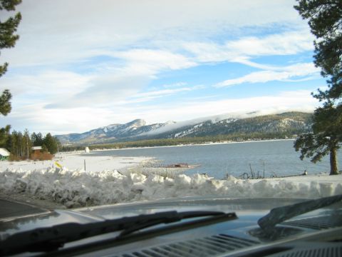 1985 Ford Bronco - View from inside a vehicle looking out at a snow-covered landscape with a lake and mountains under a cloudy sky.