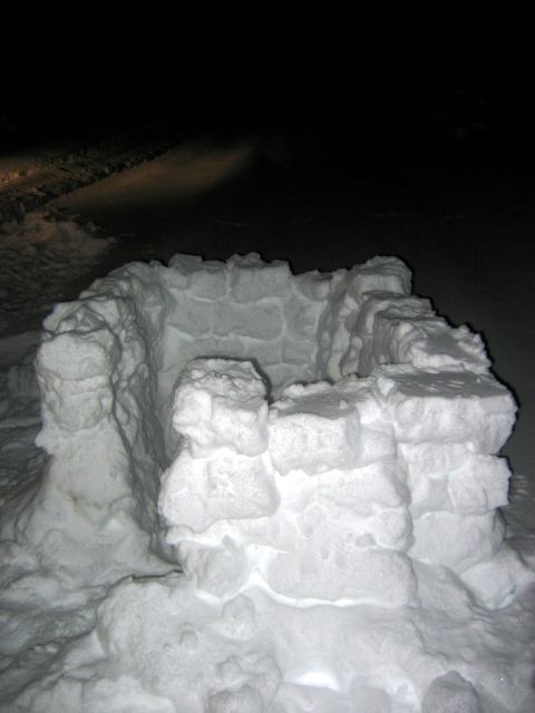 1985 Ford Bronco - A snow fort is visible at night, with headlights from an unseen vehicle illuminating the snowy ground in the background.