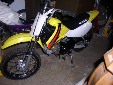 2000 Ford Excursion - A yellow Suzuki dirt bike is parked indoors, with other items partially visible in the background.