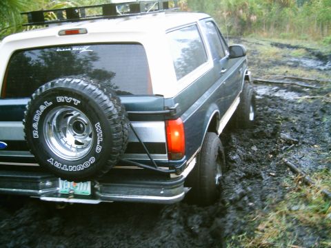 1995 Ford Bronco - Ford Bronco stuck in mud, showing rear view and spare tire. The vehicle appears to be off-roading.