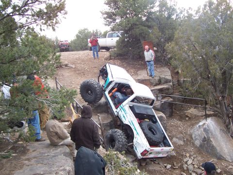 1991 Ford Bronco - An off-road vehicle navigates a challenging rocky terrain with spectators watching.