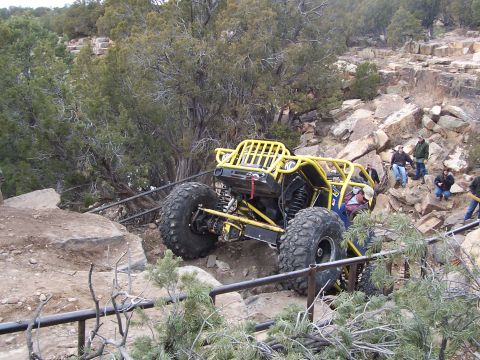 1991 Ford Bronco - A custom-built yellow off-road buggy tackles a challenging rocky trail with spectators watching.