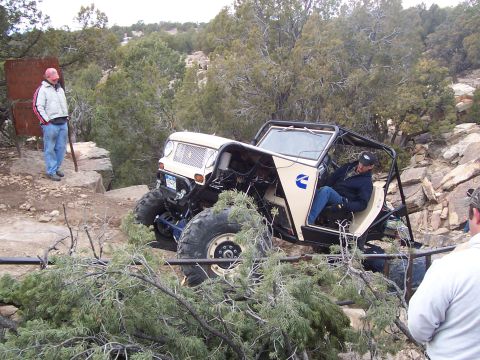 1991 Ford Bronco - A custom-built off-road vehicle tackles a challenging, rocky trail with dense vegetation.