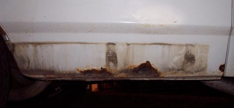1985 Ford Crown Victoria LTD - Close-up of severe rust on a vehicle's lower body panel.