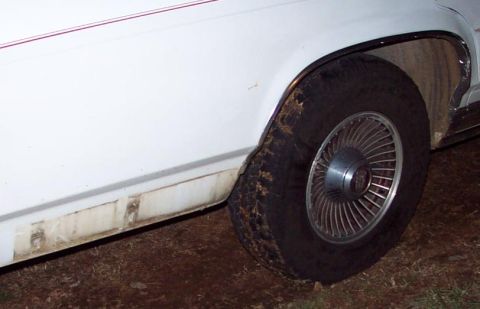 1985 Ford Crown Victoria LTD - This photo shows the side of a white vehicle, focusing on the wheel and lower body panel. The year is not definitively identifiable.