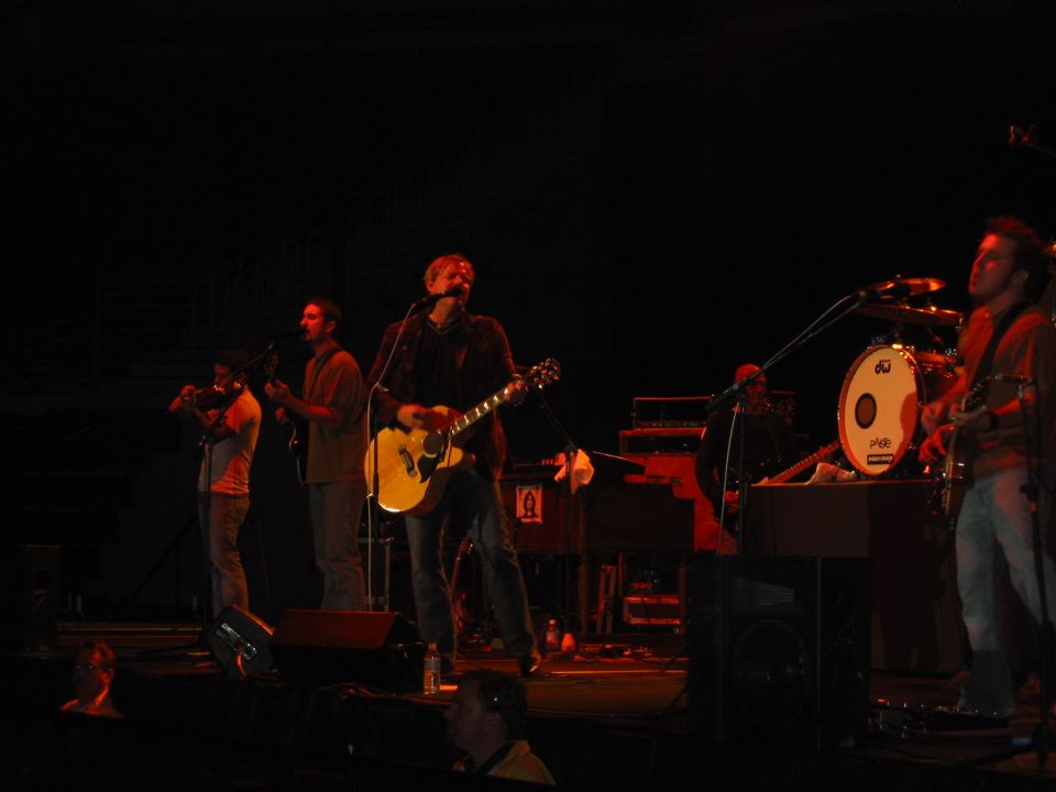 Band performing on a dimly lit stage with instruments and microphones