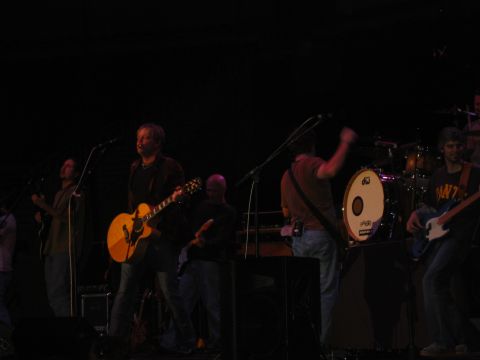 1989 Ford Bronco - A band plays on stage, illuminated by stage lights, with musicians holding guitars and a drummer visible in the background.