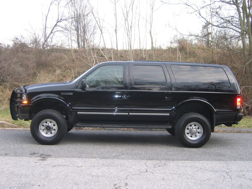 Black Ford Excursion SUV in side profile, lifted with aftermarket wheels, parked on road.