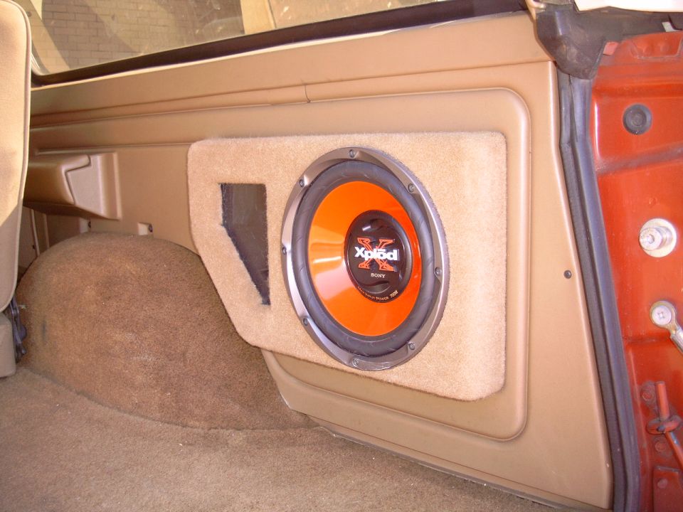 Sony Xplod subwoofer in tan carpeted box mounted in SUV rear interior panel