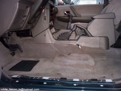 2000 Mitsubishi Montero - The interior of a vehicle is shown with the front seats removed, revealing the floor and center console area.