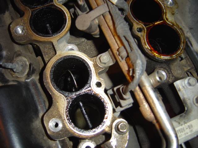 Dirty intake manifold ports with visible carbon buildup and fuel lines
