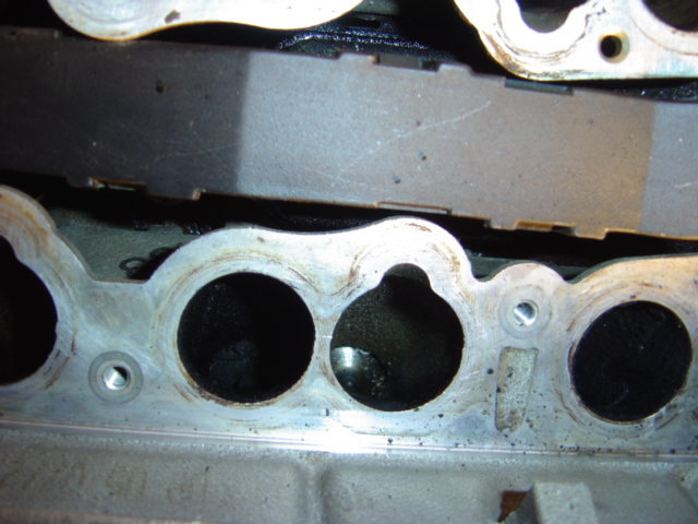 Engine intake manifold with circular ports and visible carbon buildup