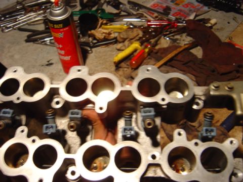 1998 Ford Taurus - Close-up of an engine intake manifold with fuel injectors, tools and a can of cleaner in the background.