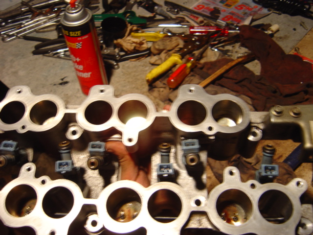Engine intake manifold with fuel injectors and a can of brake cleaner in the background