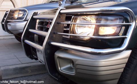 2000 Mitsubishi Montero - Close-up of the front ends of two Mitsubishi Montero SUVs, highlighting their protective bull bars and headlights.