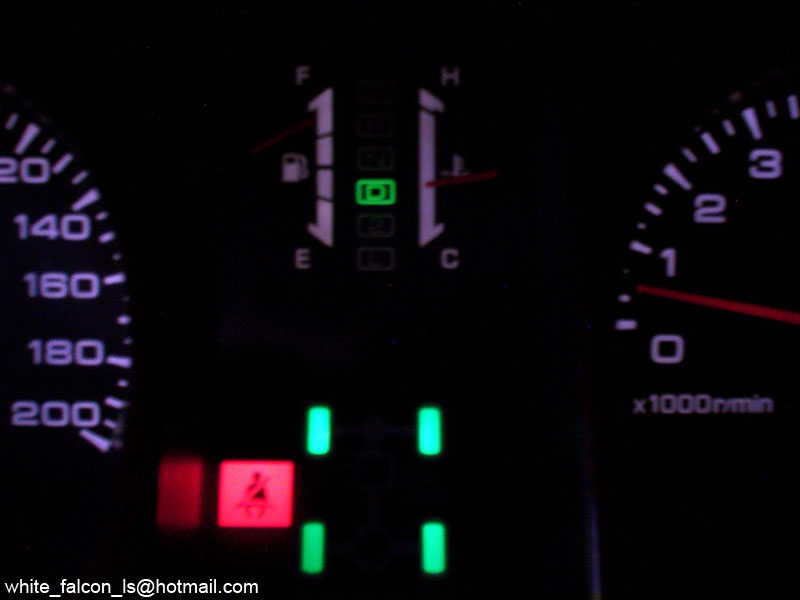 Illuminated car gauge cluster at night with speedometer, tachometer and warning lights