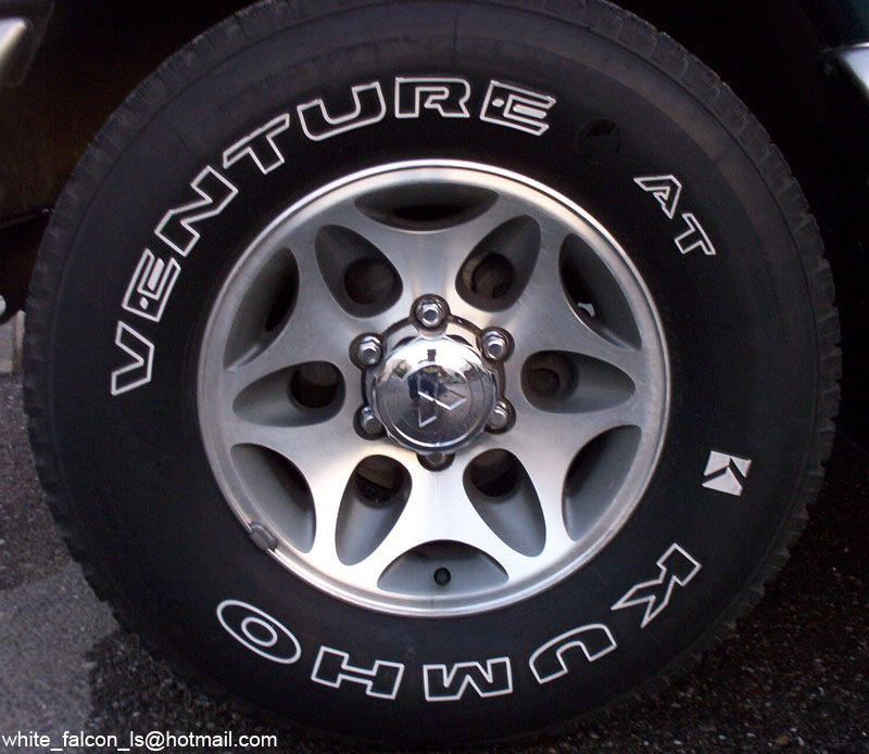 Close-up of Kumho Venture AT white-letter tire on a machined alloy wheel with Mitsubishi center cap
