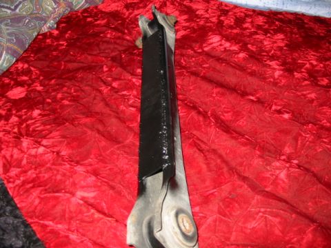 1985 Ford Crown Victoria LTD - A close-up view of a black painted metal automotive part resting on a red textured fabric background.