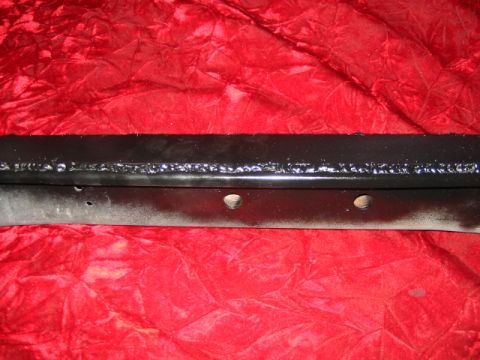 1985 Ford Crown Victoria LTD - Close-up of a black metal component, possibly a bumper reinforcement or frame piece, with visible welding and bolt holes.