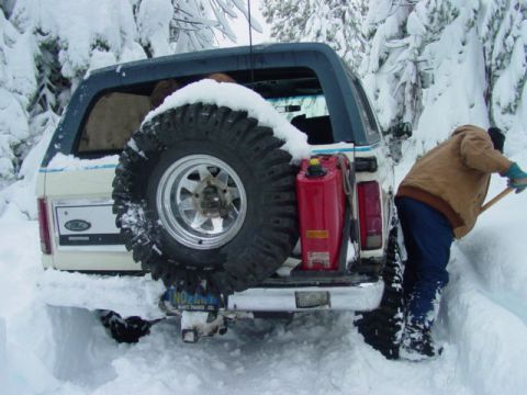 1986 Ford Bronco - Person shovels snow around a 1986 Ford Bronco stuck in a snowy environment.