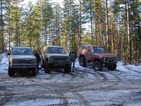1994 Ford Explorer - Three SUVs are parked in a snowy forest clearing, with two people standing near the vehicles.