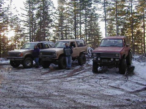 1994 Ford Explorer - Three off-road SUVs are parked in a wooded area with snow on the ground.