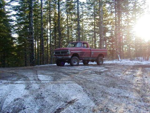 1994 Ford Explorer - A red pickup truck sits in a snowy, wooded area during sunset.